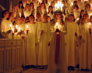 Joves cantant en el dia de Santa Llúcia i aquesta al capdavant amb la corona d'espelmes. Font: wikipedia
